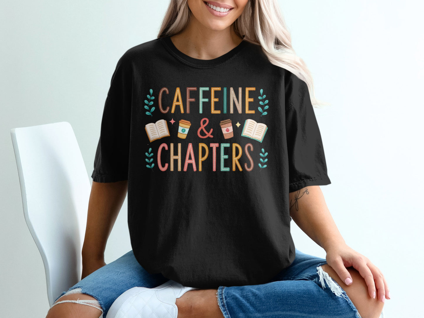 Black t-shirt with "CAFFEINE & CHAPTERS" text and book and coffee cup icons.