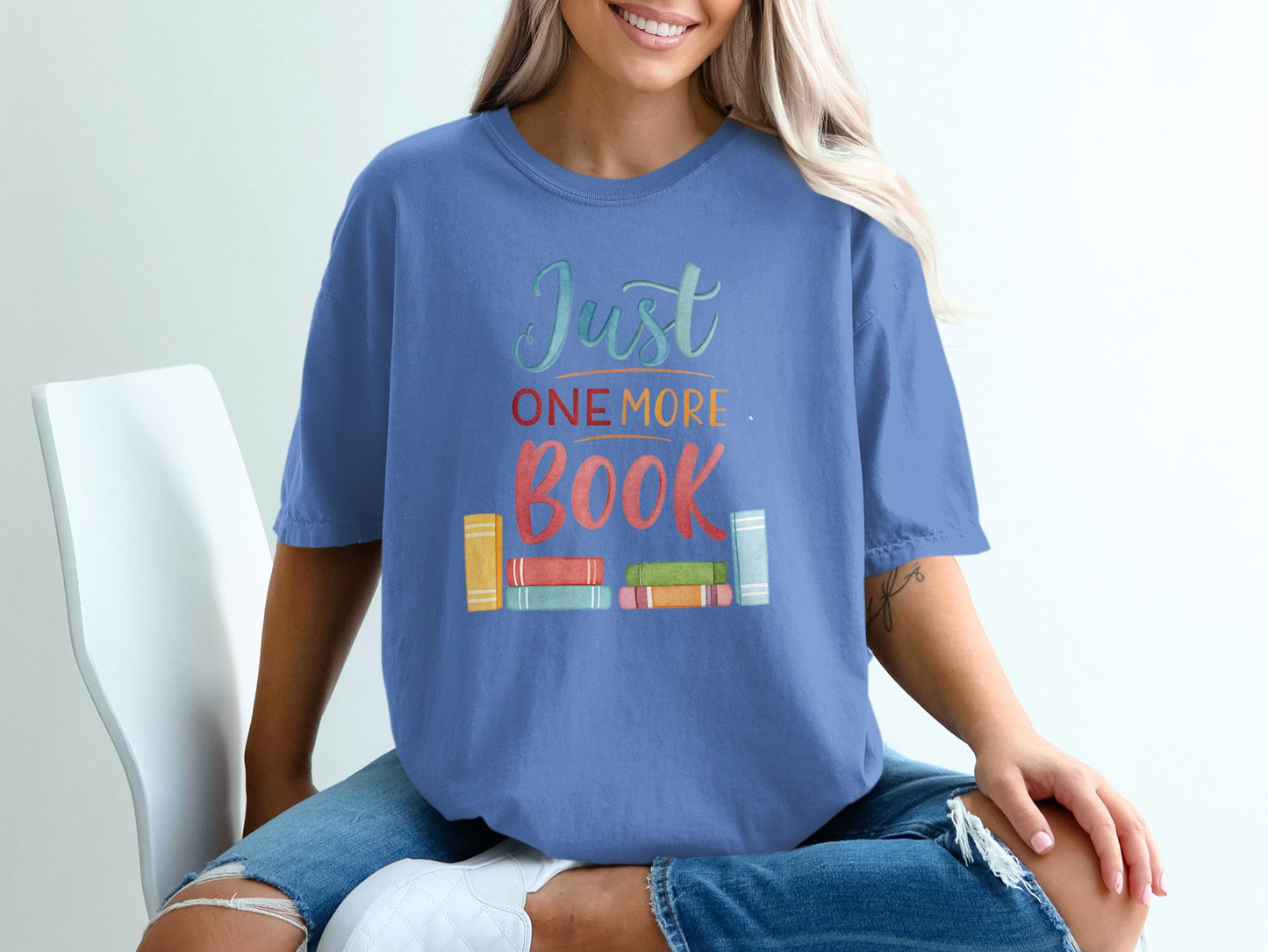 Blue t-shirt with "Just One More" and colorful book graphic.