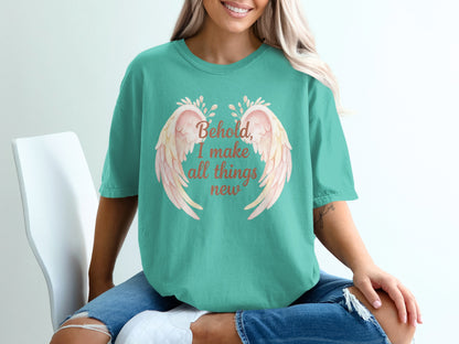 Teal t-shirt with "Behold, I make all things new" in pink wings design.