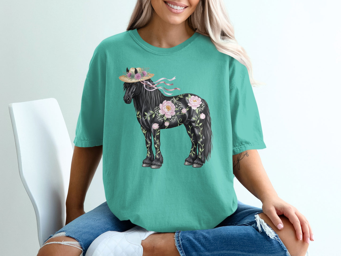 Black horse with floral accents and straw hat on teal t-shirt.