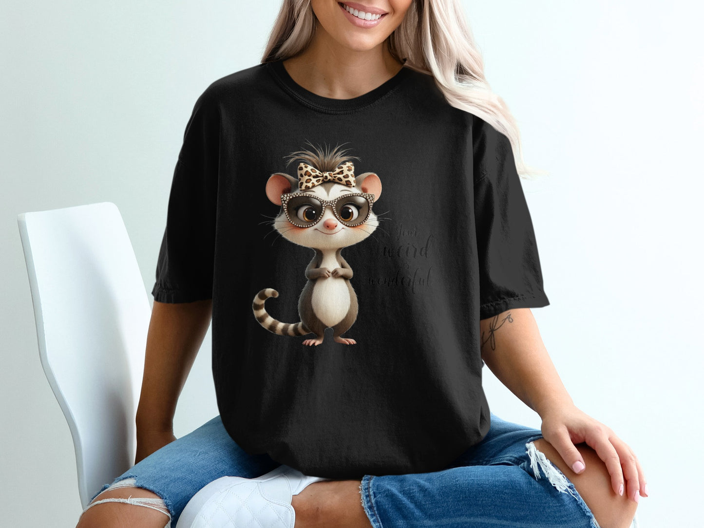 Black t-shirt with cartoon opossum wearing sunglasses and a bow.