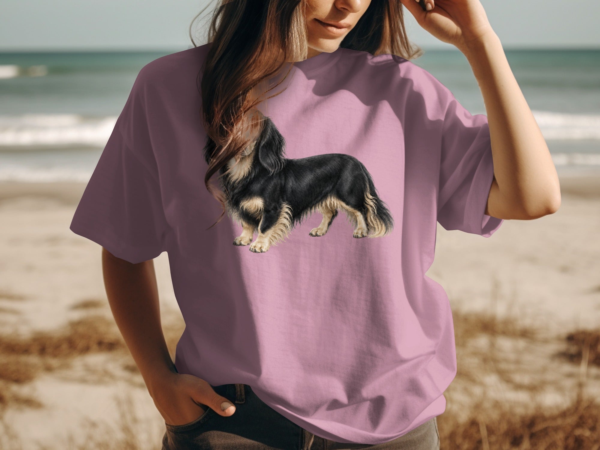 T-shirt with a long-haired black and tan dachshund graphic on a beach.
