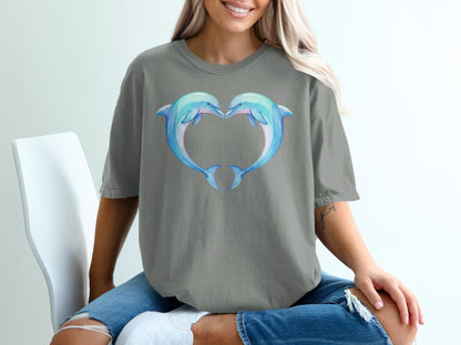 Two watercolor dolphins form a heart shape on a gray t-shirt.