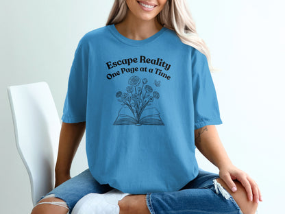 Blue t-shirt with open book, flowers, and text "Escape Reality One Page at a Time".