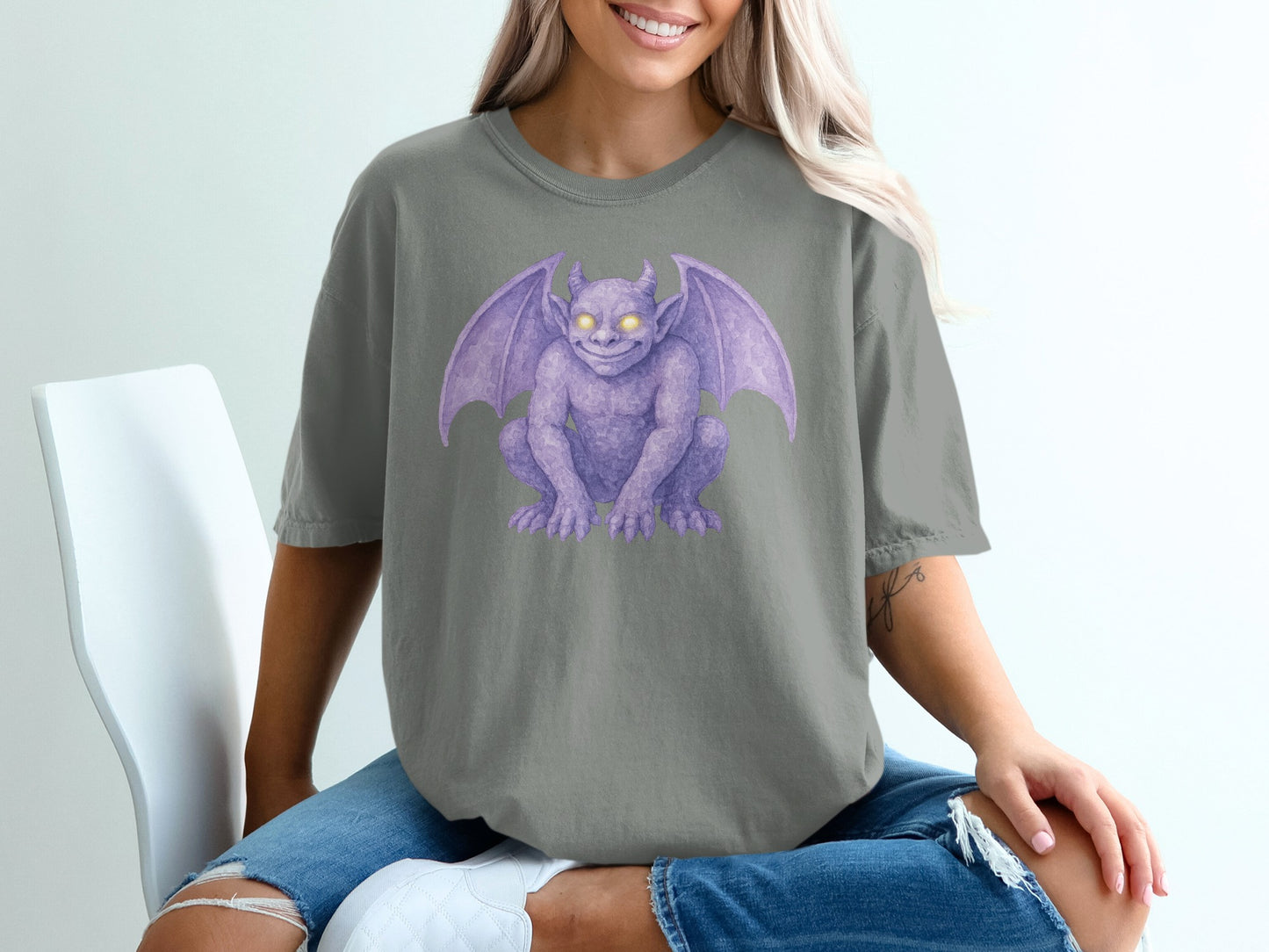Purple gargoyle illustration on a grey t-shirt worn by a woman.