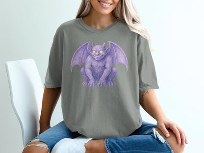 Purple gargoyle illustration on a grey t-shirt worn by a woman.