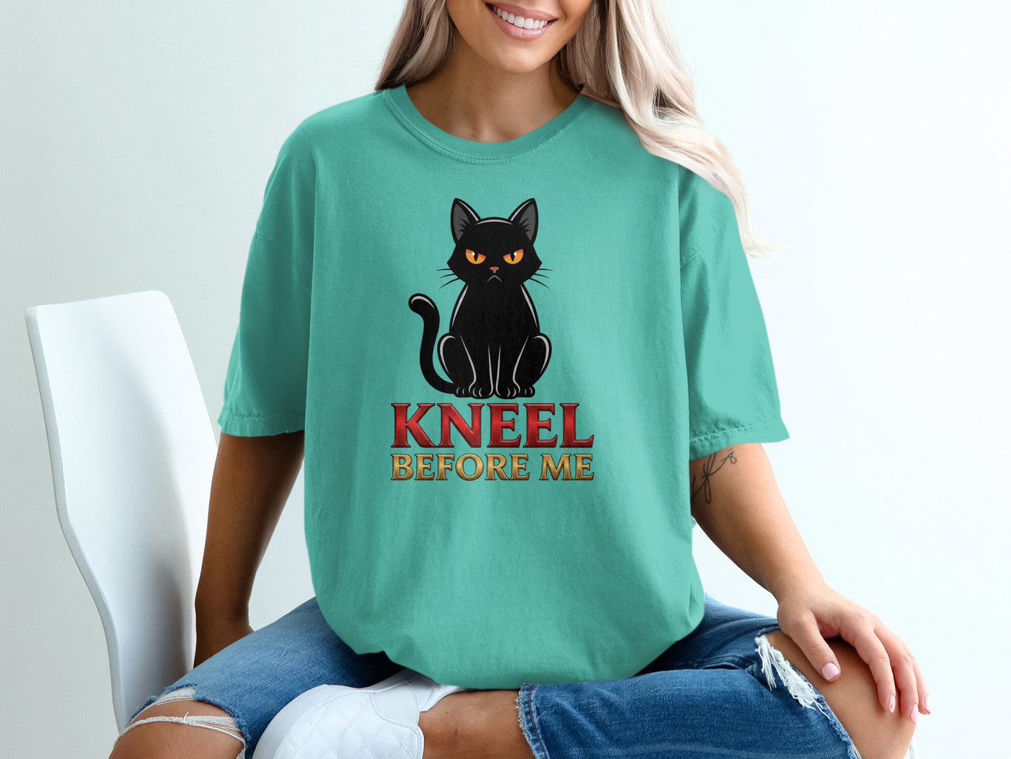 Teal t-shirt with black cat and "KNEEL BEFORE ME" text.