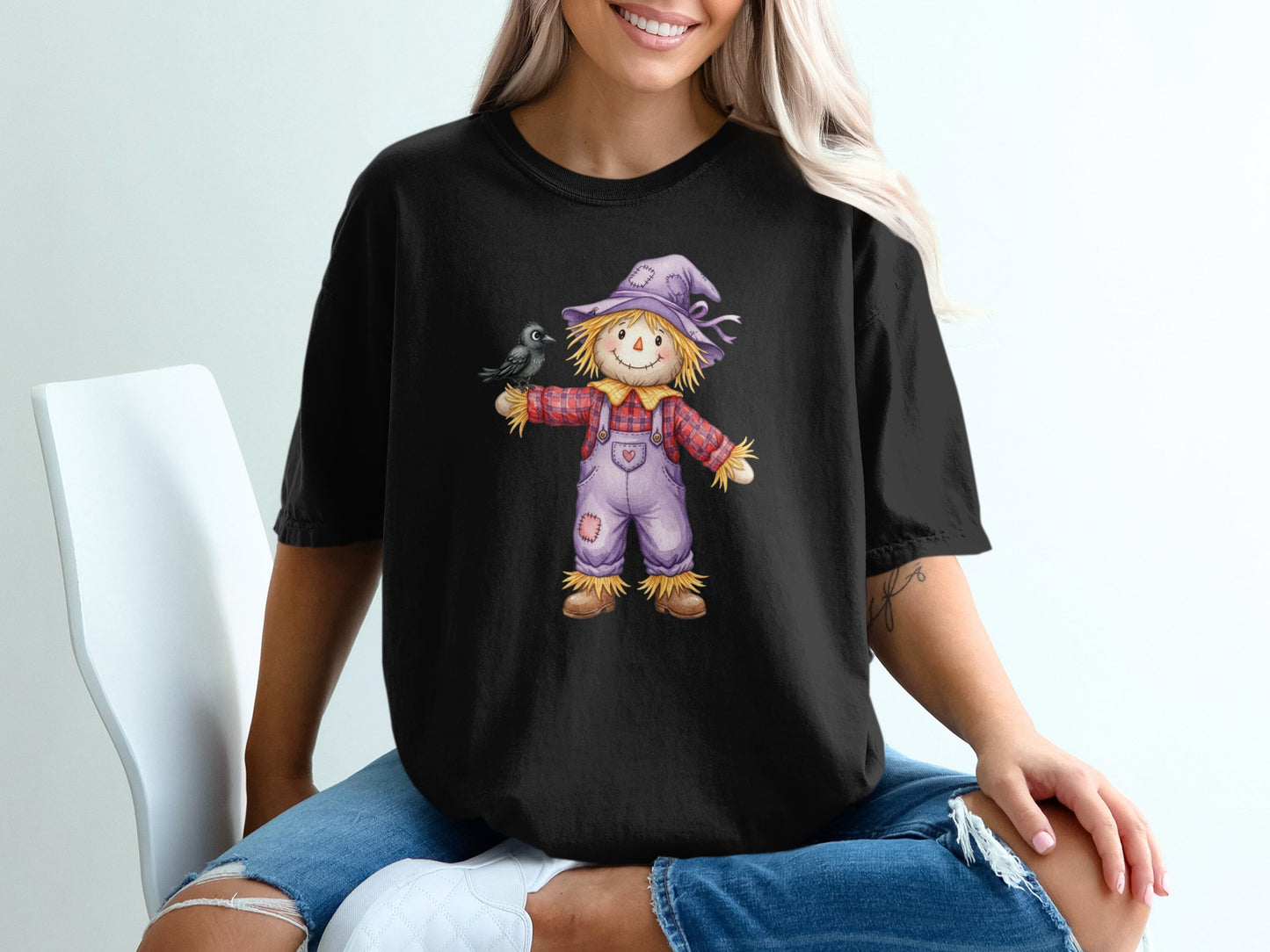 T-shirt graphic of a scarecrow with a bird on its arm.
