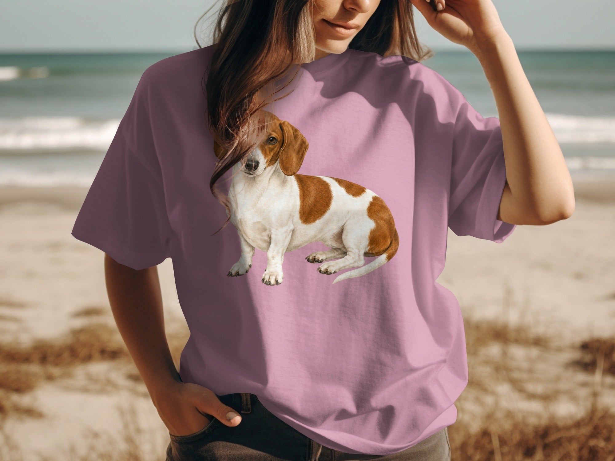 Dachshund graphic on pink t-shirt worn by a person at the beach.