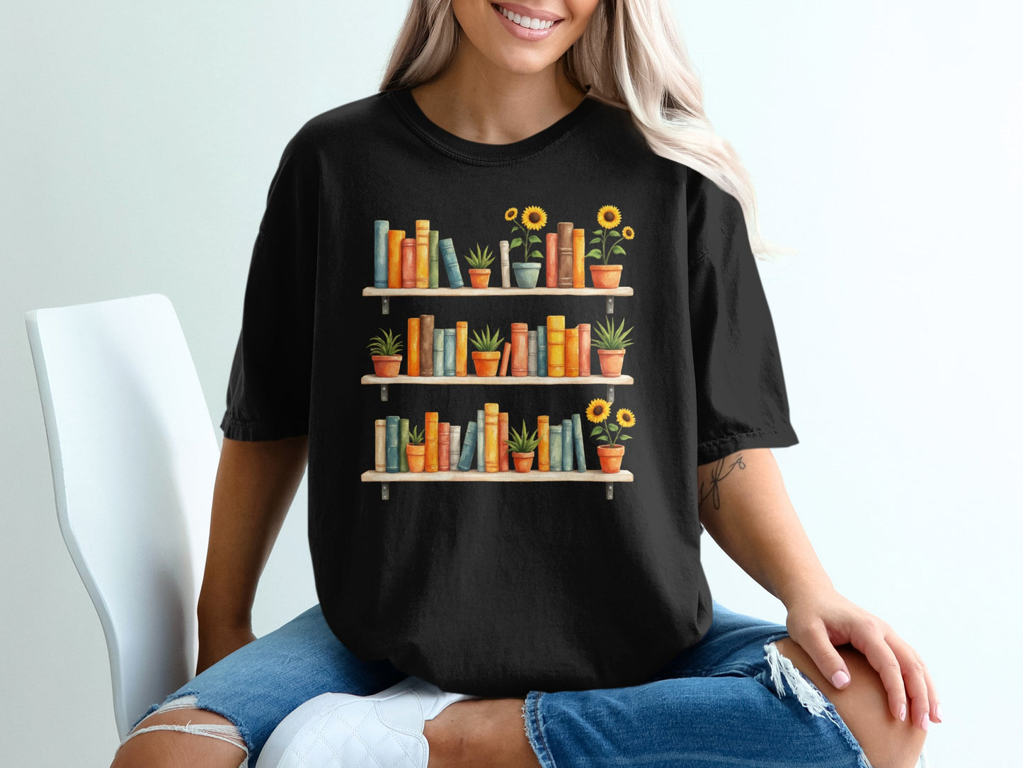Black t-shirt with a graphic of two bookshelves filled with books and potted plants.