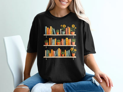 Black t-shirt with a graphic of two bookshelves filled with books and potted plants.