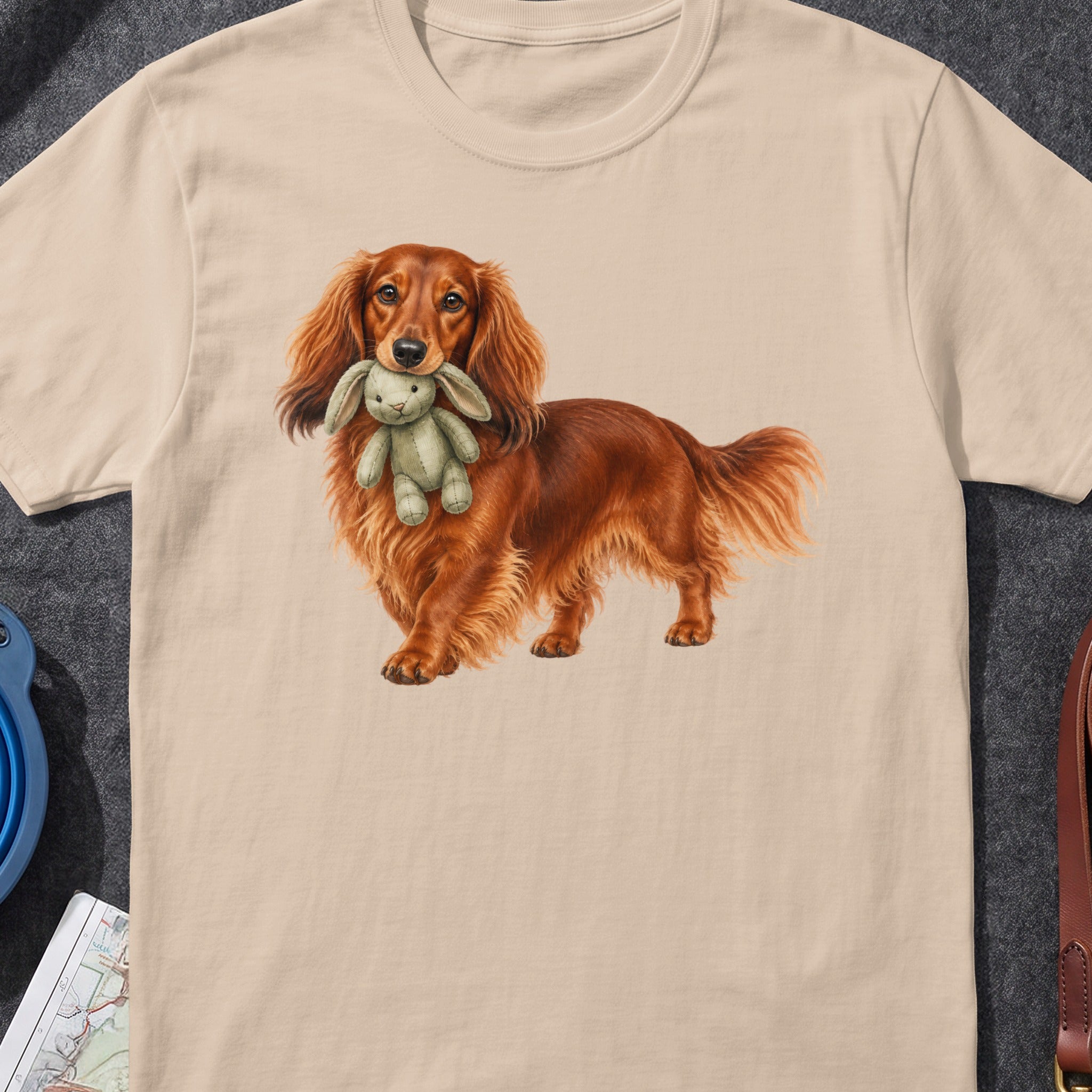Long-haired dachshund holding a stuffed bunny in its mouth.