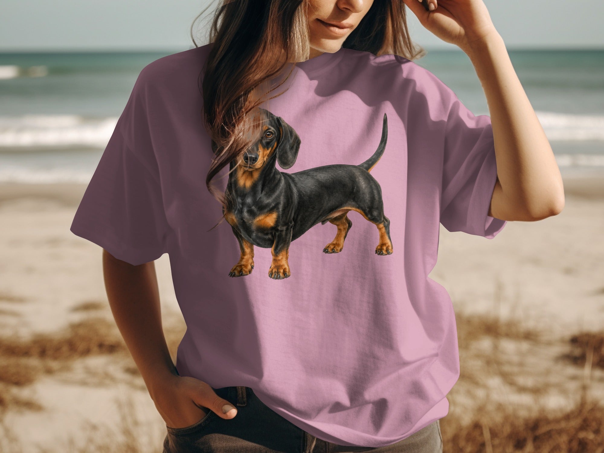 Dachshund dog illustration on a pink t-shirt worn by a person at the beach.