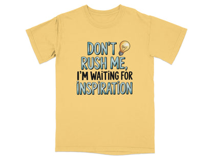 Yellow t-shirt with "Don't Rush Me, I'm Waiting for Inspiration" and a lightbulb graphic.