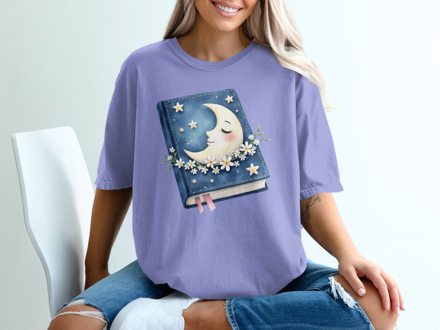 Purple t-shirt with a book, moon, and stars graphic.