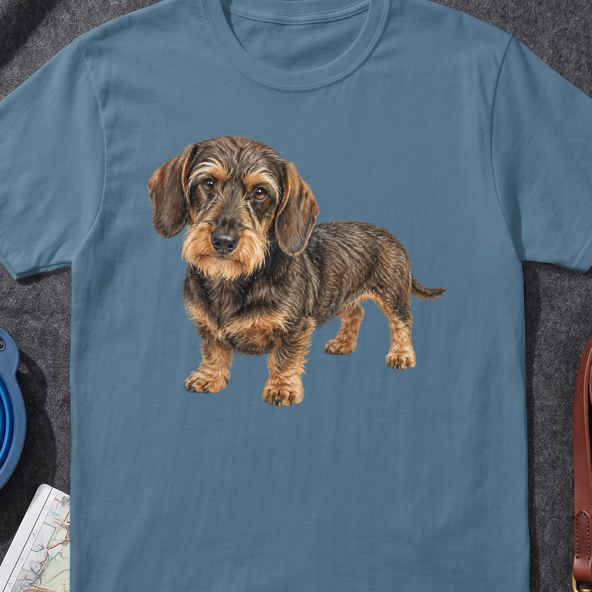 Dachshund graphic on a blue t-shirt with accessories around it.