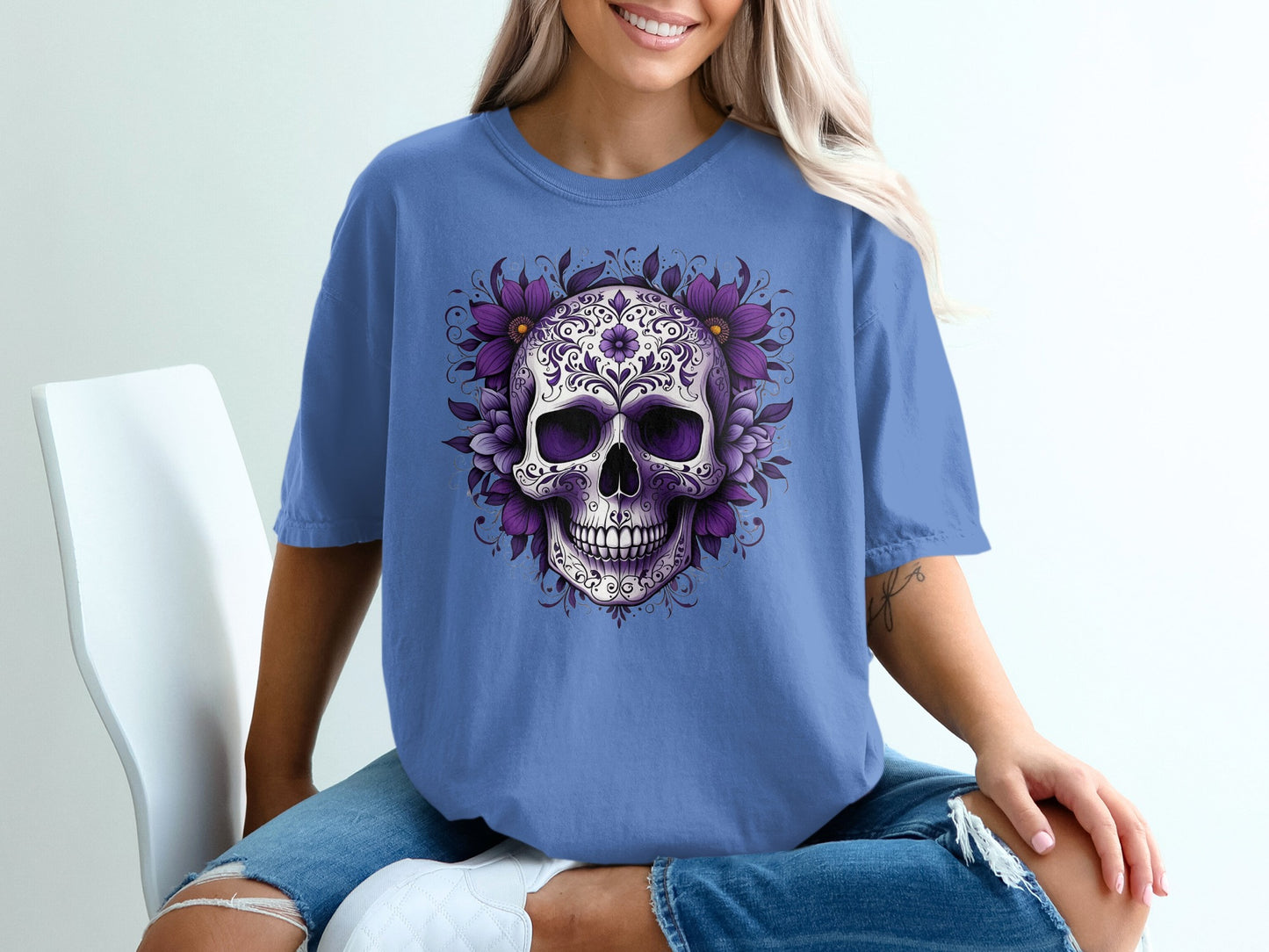 Purple floral skull graphic on a blue t-shirt worn by a woman.