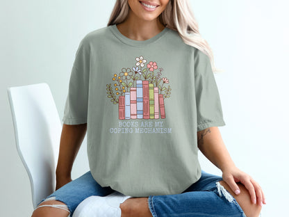 Light green t-shirt with stacked books and flowers, "Books are my coping mechanism" text.