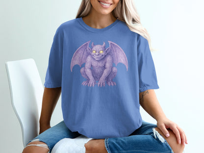 Purple gargoyle printed on a blue t-shirt worn by a woman.