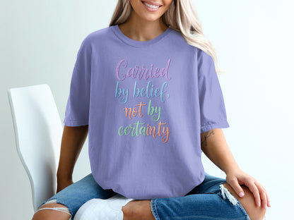 Lavender t-shirt with "Carried by belief, not by certainty" text.