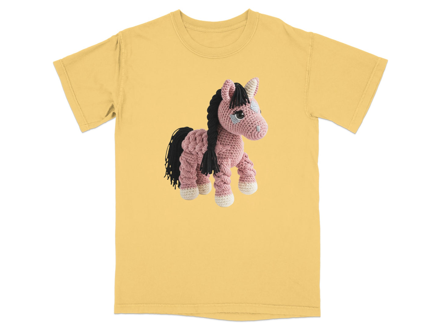 Crocheted pink unicorn with black mane and tail on yellow t-shirt.