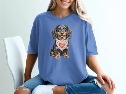 Blue t-shirt with a long-haired dachshund wearing a heart-patterned bandana.