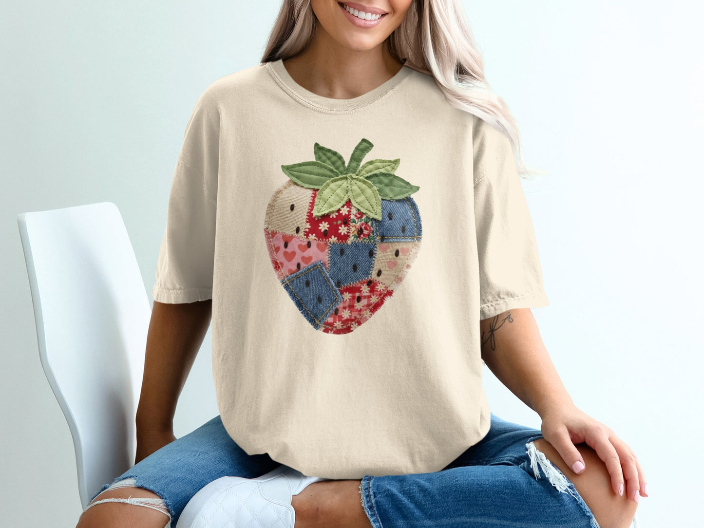 Cream t-shirt with a quilted strawberry graphic on the chest.