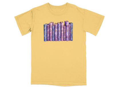 Watercolor illustration of a row of purple and blue books on a yellow t-shirt.