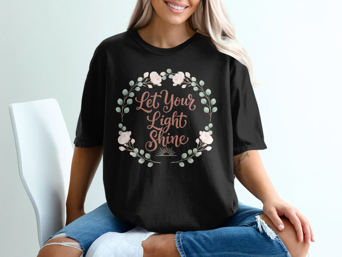 Black t-shirt with "Let Your Light Shine" text and floral wreath graphic.