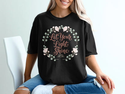 Black t-shirt with "Let Your Light Shine" text and floral wreath graphic.