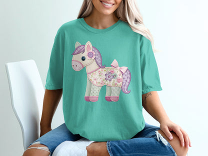 Teal t-shirt with a patchwork horse graphic featuring a pink bow.
