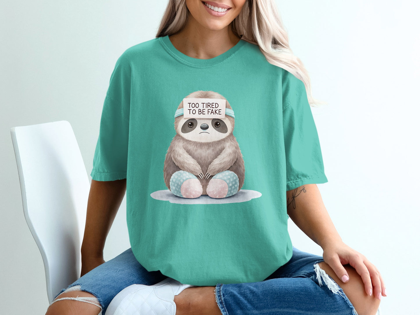 Teal t-shirt with sloth graphic and "Too Tired to Be Fake" text.