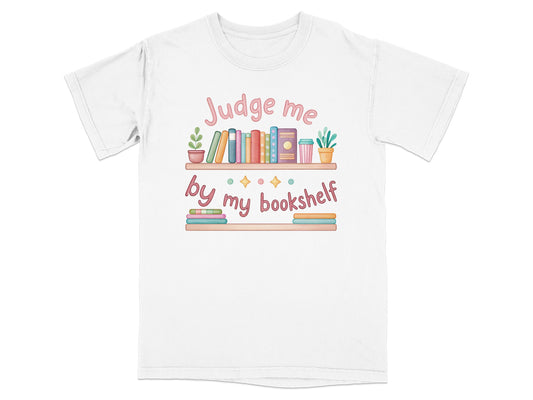 White t-shirt with "Judge me by my bookshelf" text and colorful books.
