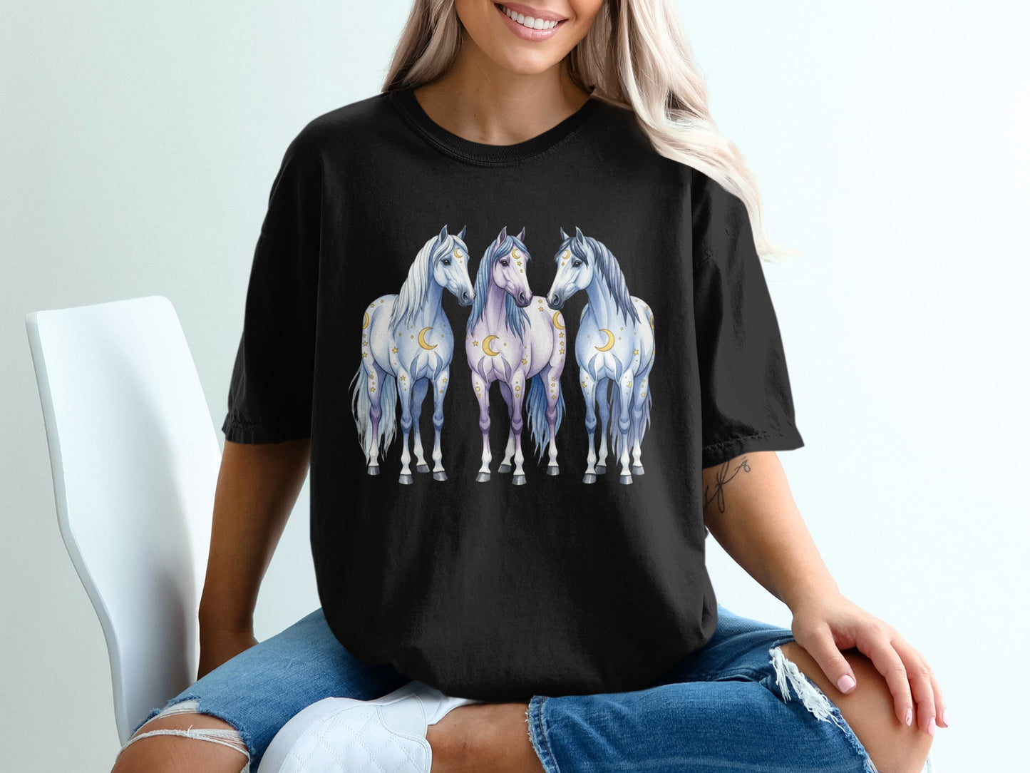 Black t-shirt with three white and grey horses adorned with moons and stars.