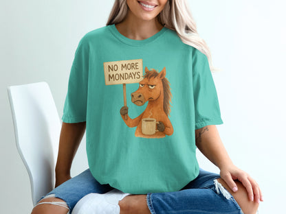 Sarcastic horse with "No More Mondays" sign and coffee cup on teal t-shirt.