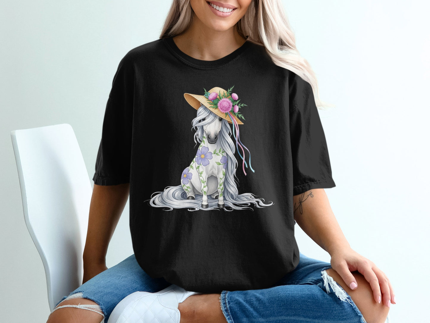 Black t-shirt with a seated white horse wearing a straw hat and flowers.