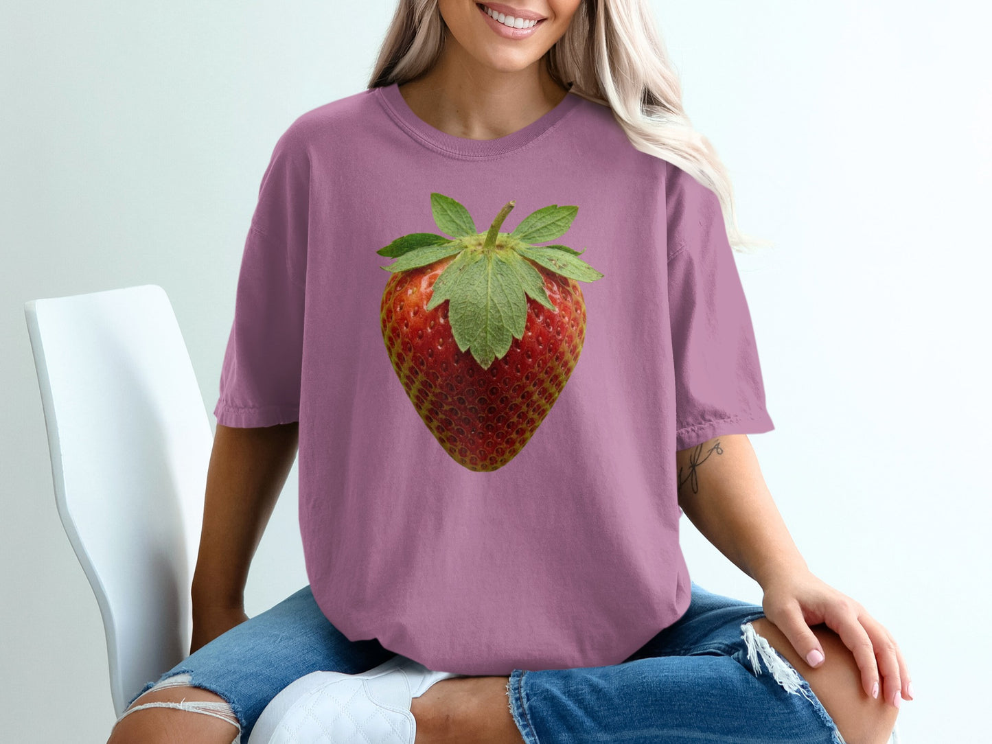 Woman wearing dusty rose t-shirt with large strawberry graphic.
