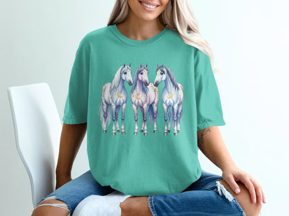 Three ethereal horses with moons and stars adorn a teal t-shirt.