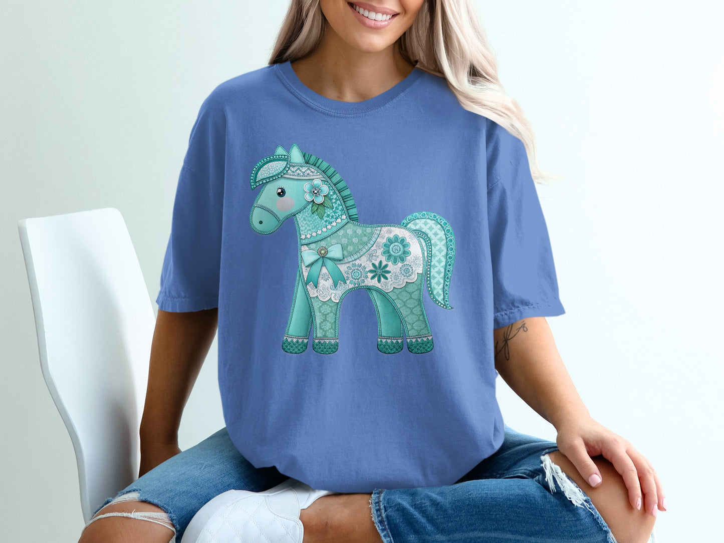Blue t-shirt with a decorative teal and white carousel horse design.