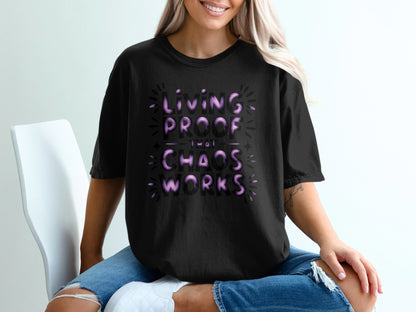 Black t-shirt with purple text reading "Living proof that chaos works".