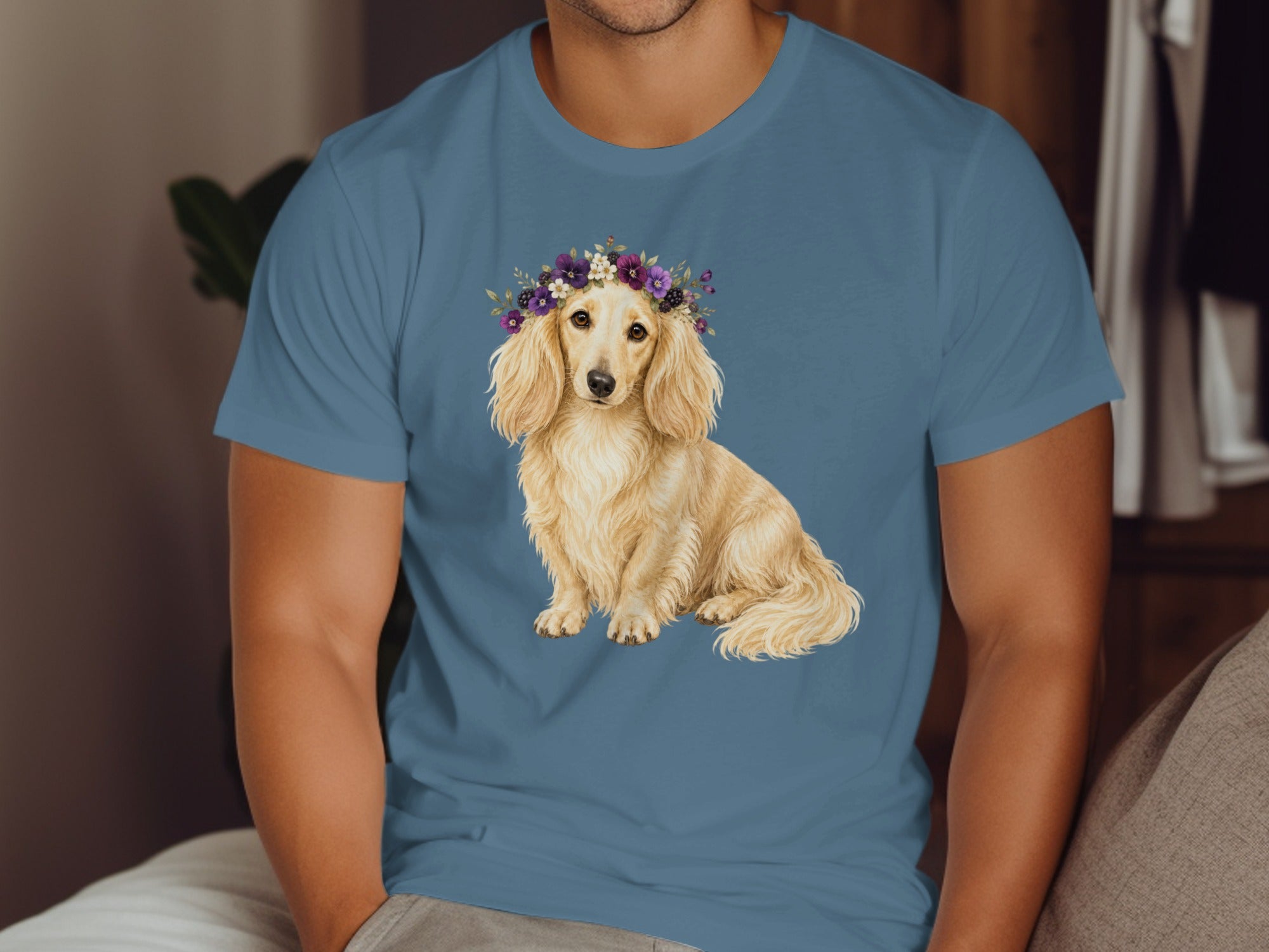 Long-haired dachshund wearing a floral crown on a blue t-shirt.