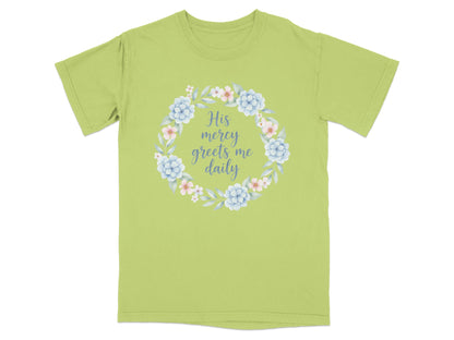 Light green t-shirt with floral wreath and "His mercy greets me daily" text.