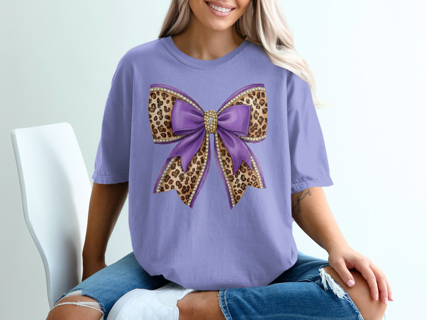 Purple bow with leopard print and rhinestones on a lavender t-shirt.
