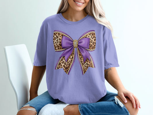 Purple bow with leopard print and rhinestones on a lavender t-shirt.