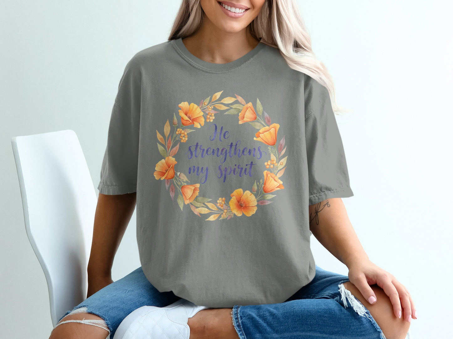Grey t-shirt with floral wreath and "He strengthens my spirit" text.