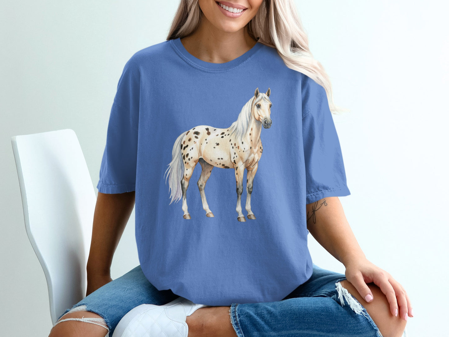 Watercolor painting of a spotted Appaloosa horse on a blue t-shirt.