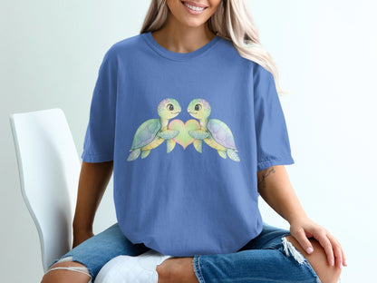 Two cartoon turtles embracing a pastel heart on a blue t-shirt.