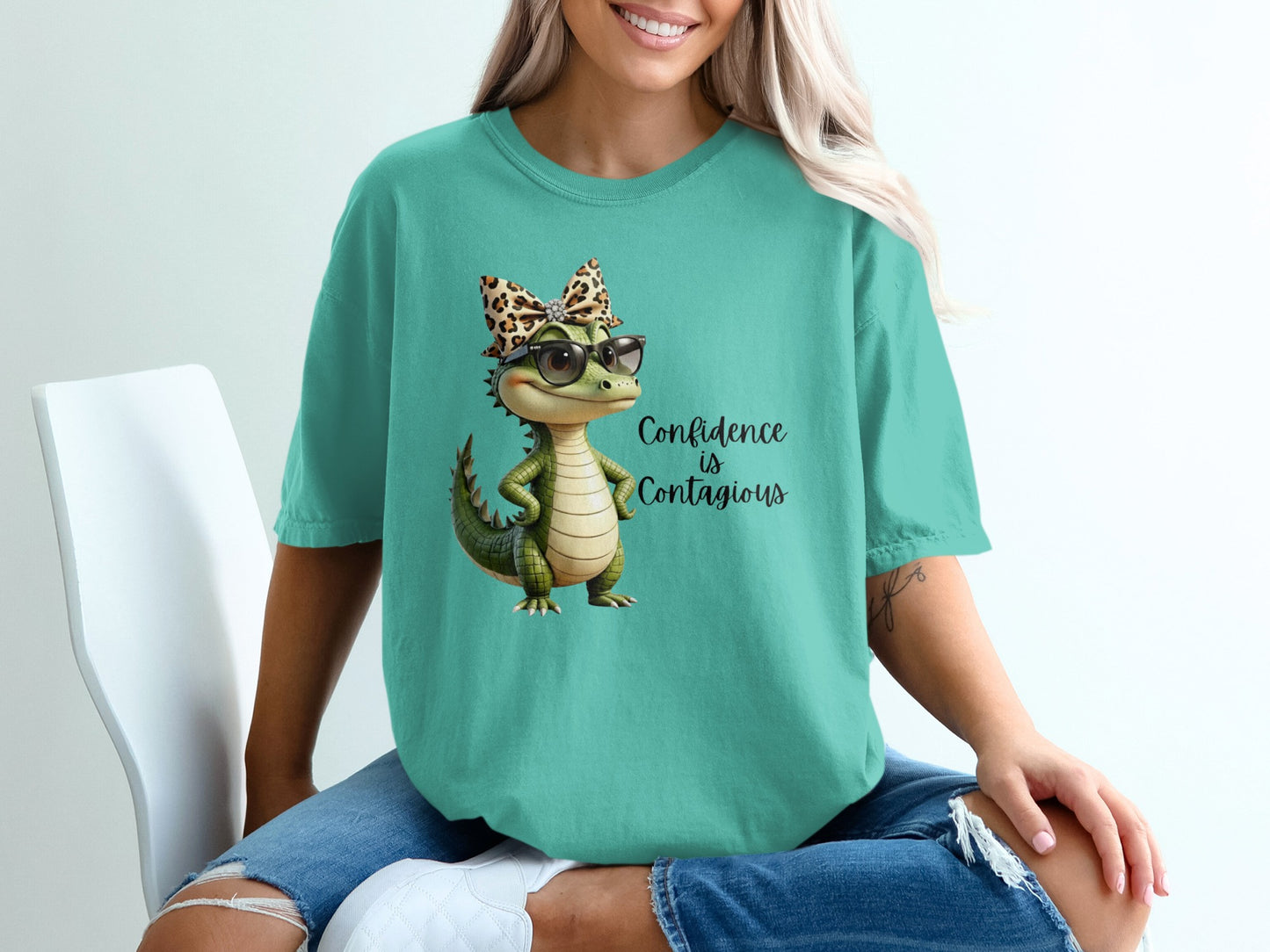 Teal t-shirt with a cartoon alligator wearing glasses and a leopard print bow.