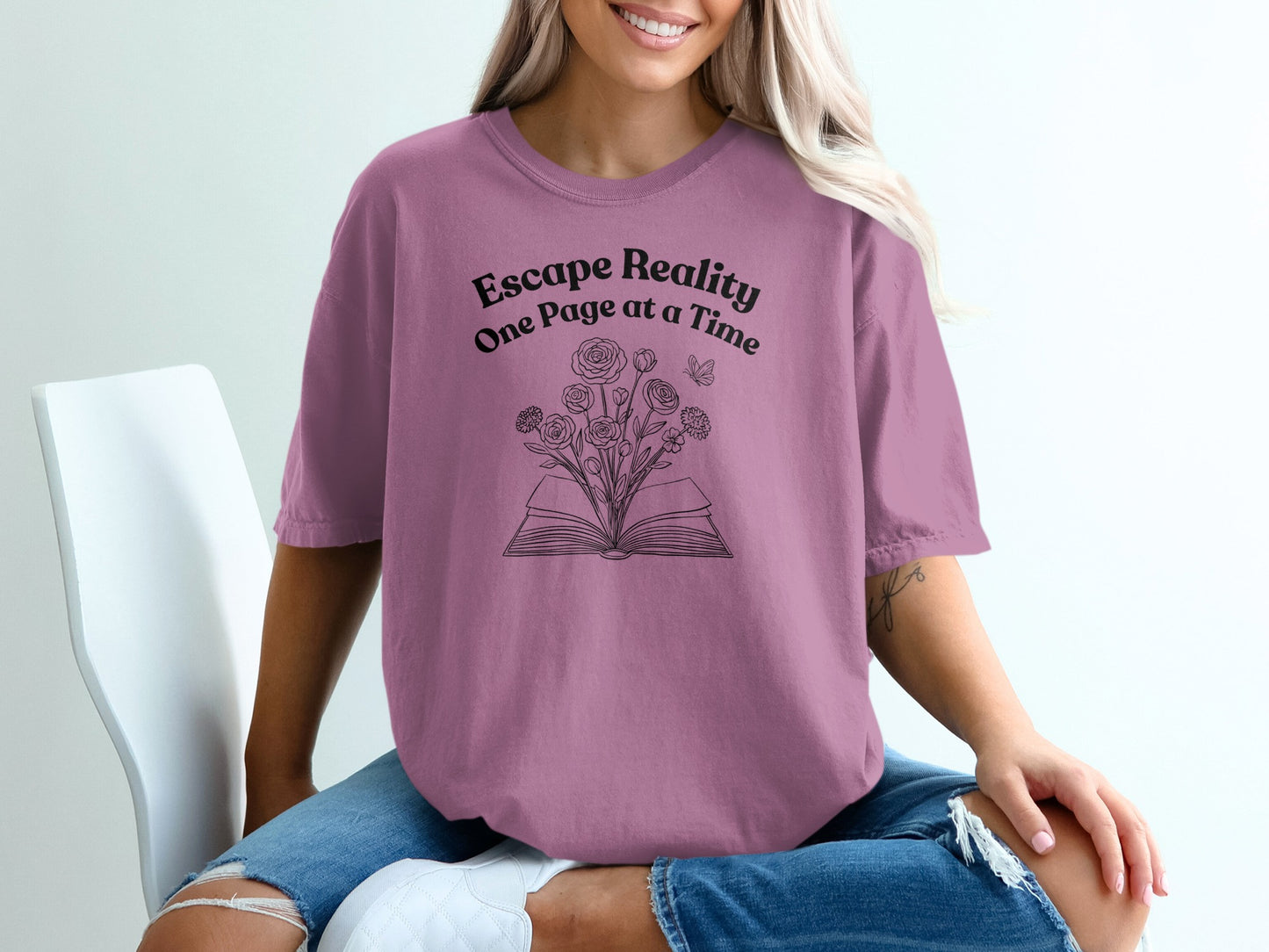Purple t-shirt with "Escape Reality One Page at a Time" and open book with flowers.