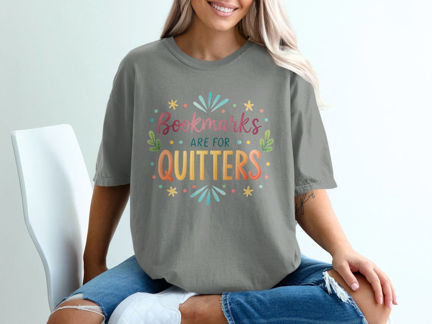 Grey t-shirt with colorful "Bookmarks are for quitters" text and designs.